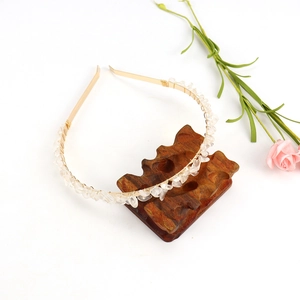 Detail of handmade gold wire-wrapped headband with natural clear crystal stones on a stand