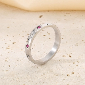 Détail d'une bague étoile argentée sertie de zircons roses et blancs sur support pierre