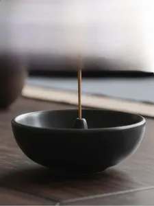 Macro shot of matte black ceramic incense burner bowl with centered holder for incense sticks