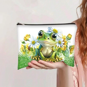 Détail d'une pochette en toile avec motif grenouille et tournesol tenue à la main