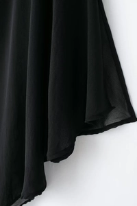 Gros plan sur l'ourlet en mousseline noire avec coutures précises et texture légère