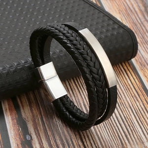 Detail of multi-layer black braided leather bracelet with silver magnetic clasp and metal plate