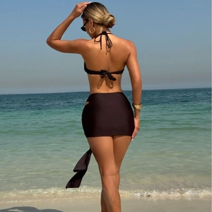 Three-piece black bikini set with halter top and mini skirt shown from a back view at the beach