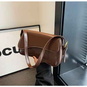 Detail of a dark brown glossy PU leather shoulder bag with elegant golden hardware buckle