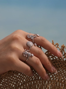 Detailed view of silver sea creature rings with zircon stones worn during a summer vacation