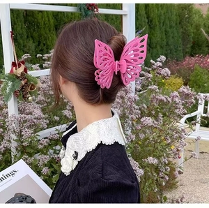 Detail shot of a large double-layered pink butterfly hair claw clip worn by a model