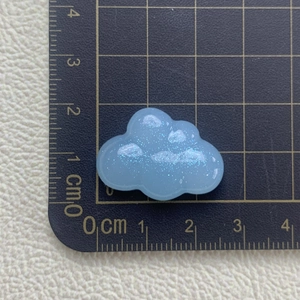 Close-up of a blue resin cloud accessory with glitter on a measuring mat for crafts