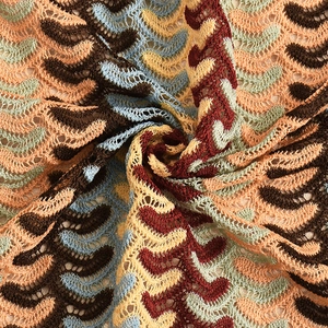Detailed macro shot of wavy crochet knit fabric in brown, blue and coral pink tones