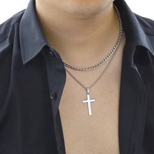 Close-up of men's double-layered silver curb chain and cross pendant on a model