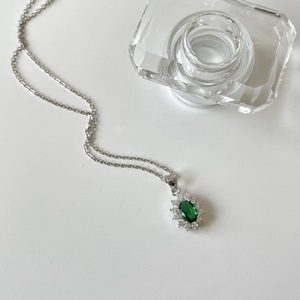 Macro shot of 925 silver necklace featuring an emerald green zircon pendant with crystals