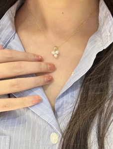 Macro shot of gold petal pendant with pink pearls and zircon on a model neck