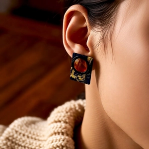 Close-up of retro resin square earrings with gold splash and amber bead on model's ear