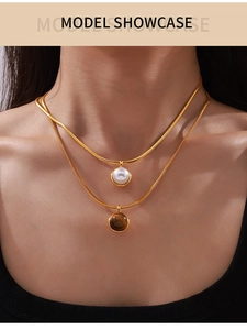Close-up of double layer gold snake chain necklace with pearl and tiger eye stone pendants