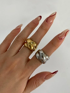 Close-up of interlocking twisted wide band rings in polished gold and silver finishes