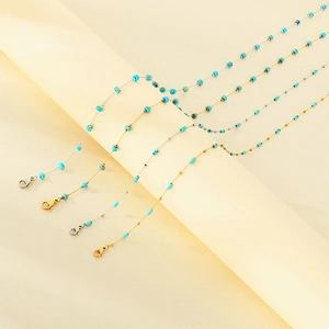 Detailed view of gold and silver stainless steel chains with turquoise bead accents