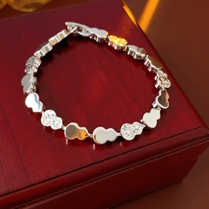 Detailed view of silver gourd bracelet with polished and textured links on wood