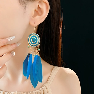 Detail of blue feather tassel earrings on model showing bohemian vintage style texture