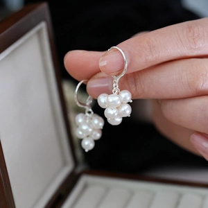 Detailed macro view of a cluster grape earrings with white pearls and silver hooks