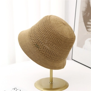 Knitted khaki bucket hat for women with JSHAT metal tag on a minimalist stand