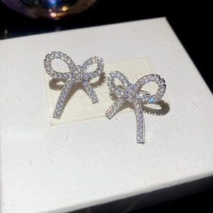 Macro shot of silver bow ear clips featuring shimmering cubic zirconia on white card
