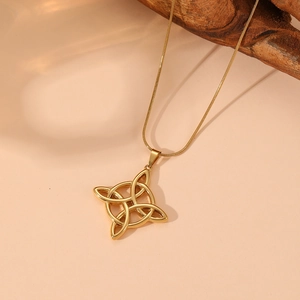 Detailed shot of a gold Celtic knot pendant with snake chain on a soft peach background