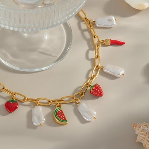 Collier doré avec pendentifs fraise, pastèque et perle sur accessoires de plage