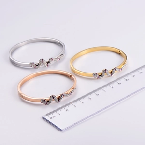 Detailed view of snake-shaped bracelets in silver, gold, and rose gold with zircon inlay