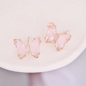 Close-up of pink butterfly stud earrings with gold plating and sparkling zircon stones