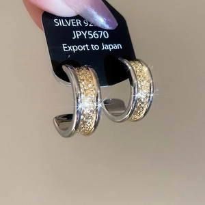 Detail shot of two-tone C-shape earrings in 18k gold plating and 925 silver finish