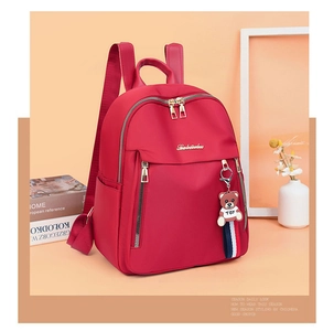 Detail of red oxford nylon backpack with gold zippers and a cute teddy bear charm