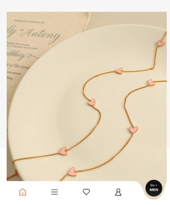 Detail of pink enamel heart pendants on a delicate gold chain necklace over vintage paper