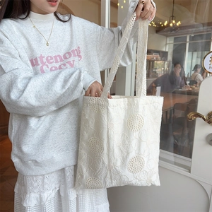 Detail of white hollow-out lace floral embroidery on large canvas tote bag for women