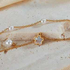 Macro view of gold flower pendant with mother of pearl and pearls on layered necklace