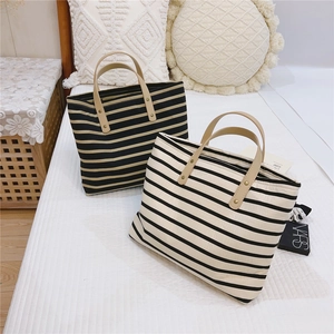 Detail of striped canvas tote bags with brown faux leather handles and rivet accents