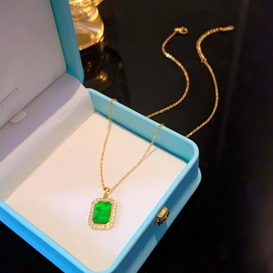 Minimalist gold titanium necklace with green square gemstone pendant in jewelry box