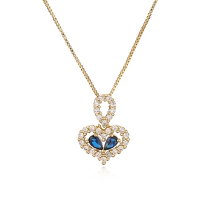 Detailed close-up of a gold heart pendant with clear diamonds and blue gemstones