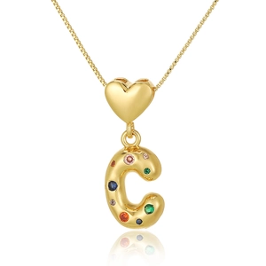 Macro shot of gold heart necklace with colorful zircon encrusted letter C pendant