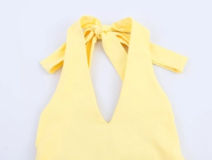 Detail of a bright yellow halter neck top with deep V-neckline and stylish bow tie design