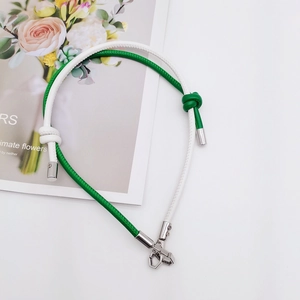 Detail view of green and white leather lanyard with silver geometric metal clasp
