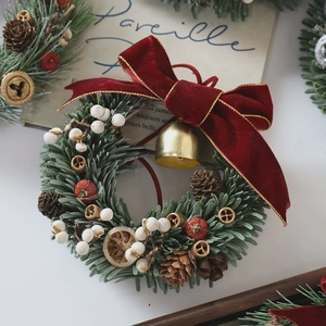 Handmade Christmas wreath with pine cones, red berries, velvet bow and golden bell