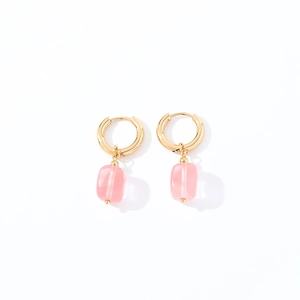 Close-up of geometric gold hoop earrings with pink translucent rectangular stone drops