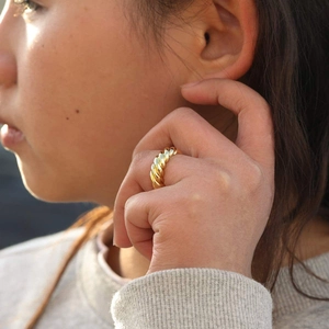 Close-up of 18K gold-plated croissant ring on finger with high-polish finish