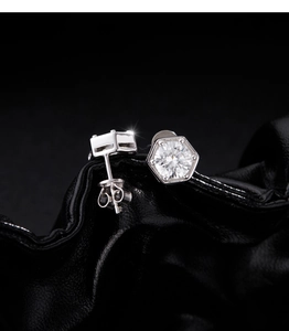 Macro shot of 1 carat moissanite hexagonal stud earrings on black leather background