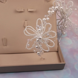 Detailed close-up of bridal headband featuring handcrafted pearl and crystal flower motifs
