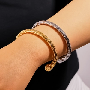 Irregular hammered 18k gold and silver stainless steel lava bangles on model's wrist