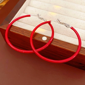 Close-up of vintage red hoop earrings on a leather surface and wooden jewelry box
