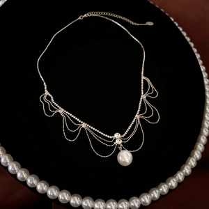 Detailed view of silver tassel necklace with pearl pendant and sparkling rhinestones