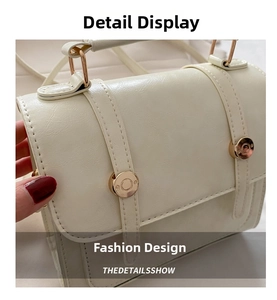 Macro detail of creamy faux leather handbag featuring dual gold snap buttons and top handle