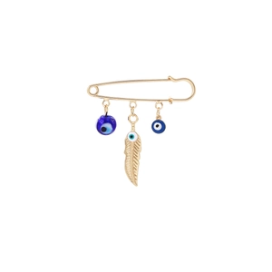 Detail of gold safety pin brooch with blue evil eye beads and hanging feather pendant