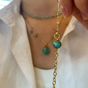 Close-up of a gold titanium bracelet featuring a round faceted turquoise gemstone detail